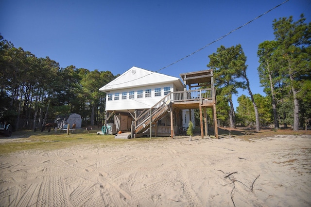 back of house featuring a shed, stairs, a deck, and an outdoor structure