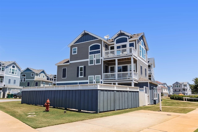 view of front of property with driveway, board and batten siding, a front yard, and a residential view