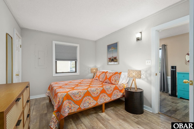 bedroom with a textured ceiling, baseboards, and wood finished floors