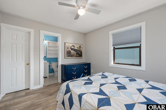 bedroom featuring a ceiling fan, connected bathroom, light wood-style flooring, and a textured ceiling