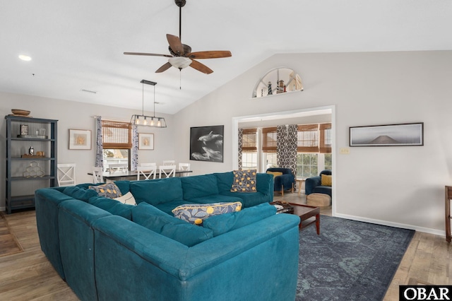 living area featuring lofted ceiling, visible vents, a ceiling fan, wood finished floors, and baseboards