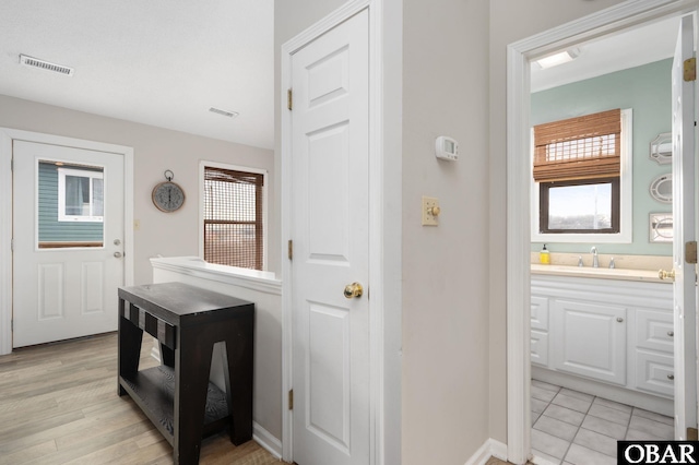 interior space with vanity, plenty of natural light, wood finished floors, and visible vents