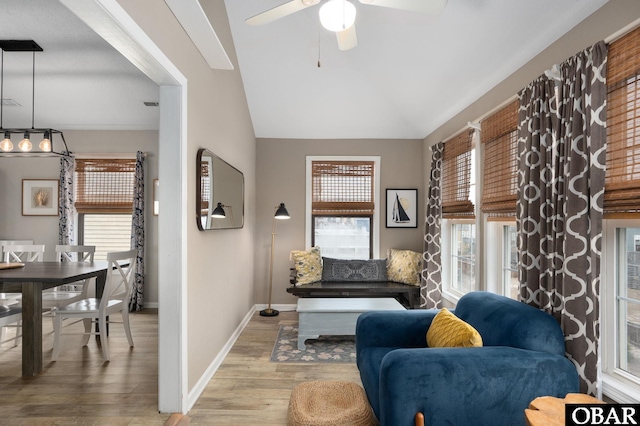 living area featuring vaulted ceiling, ceiling fan, wood finished floors, and baseboards