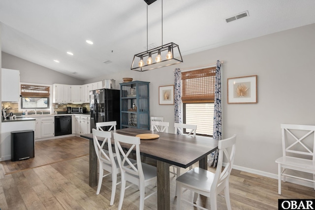 dining area featuring visible vents, baseboards, light wood-style flooring, vaulted ceiling, and recessed lighting