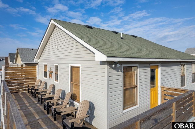 rear view of property featuring a wooden deck and roof with shingles