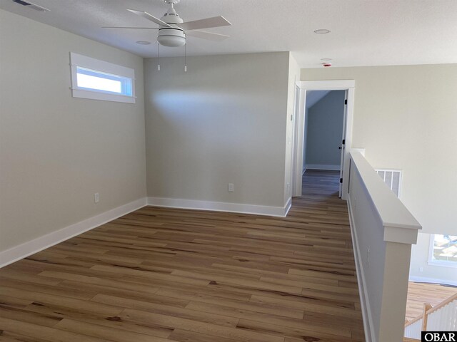 spare room with ceiling fan, dark wood finished floors, visible vents, and baseboards