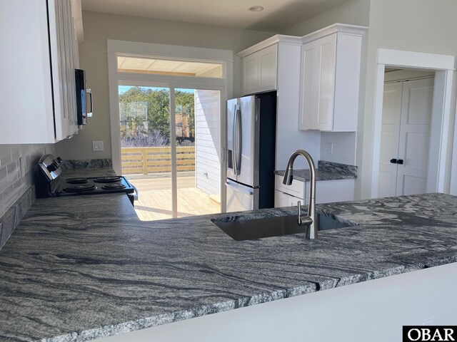 kitchen featuring stainless steel appliances, a sink, white cabinetry, and decorative backsplash