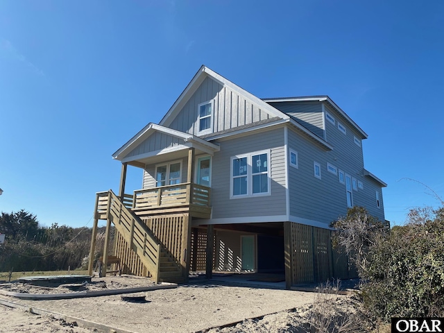 coastal inspired home featuring a carport, covered porch, driveway, and board and batten siding