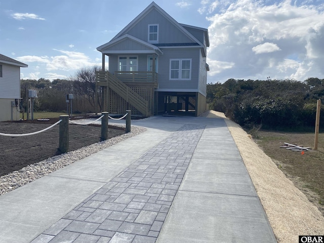 beach home with driveway, covered porch, and stairs