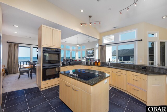 kitchen with a sink, light brown cabinetry, black appliances, and dark tile patterned flooring