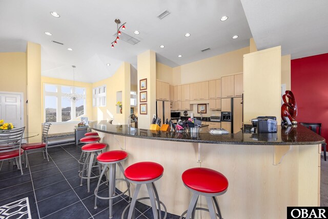 kitchen with paneled fridge, a breakfast bar area, a peninsula, fridge, and light brown cabinetry