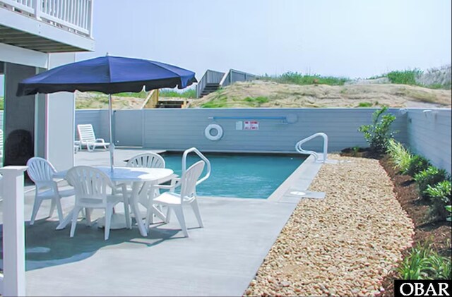 community pool with outdoor dining space, a fenced backyard, and a patio