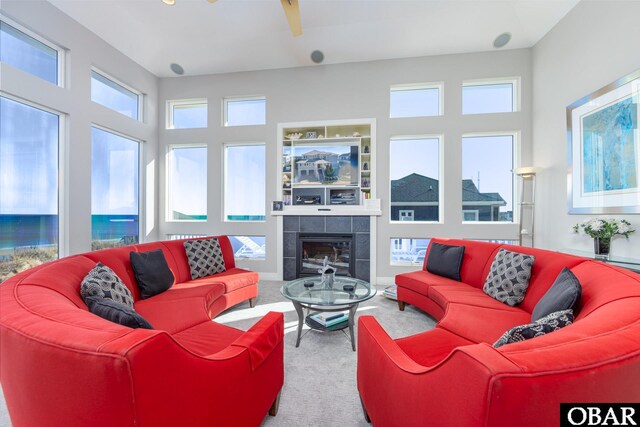 living room with ceiling fan, carpet floors, and a tile fireplace