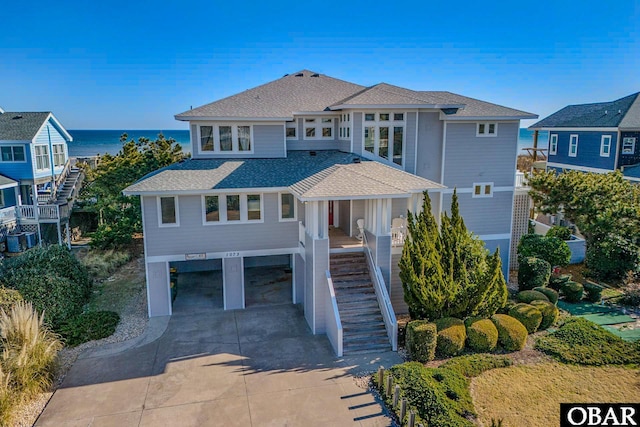 beach home with driveway, stairway, roof with shingles, covered porch, and a carport