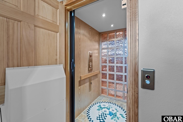 bathroom with a textured wall, recessed lighting, and elevator