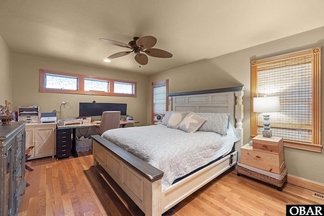 bedroom with ceiling fan, light wood finished floors, and baseboards