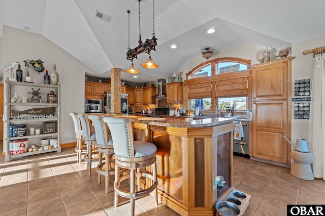 kitchen with vaulted ceiling, wall chimney exhaust hood, hanging light fixtures, and a kitchen island