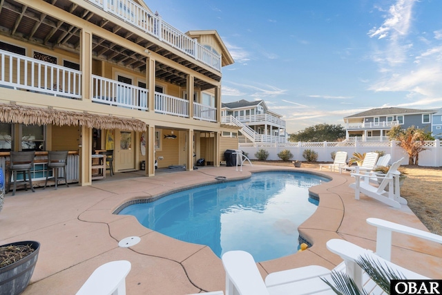 view of pool featuring area for grilling, fence, a fenced in pool, a bar, and a patio area