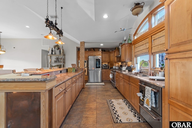 kitchen featuring pendant lighting, recessed lighting, appliances with stainless steel finishes, a sink, and vaulted ceiling