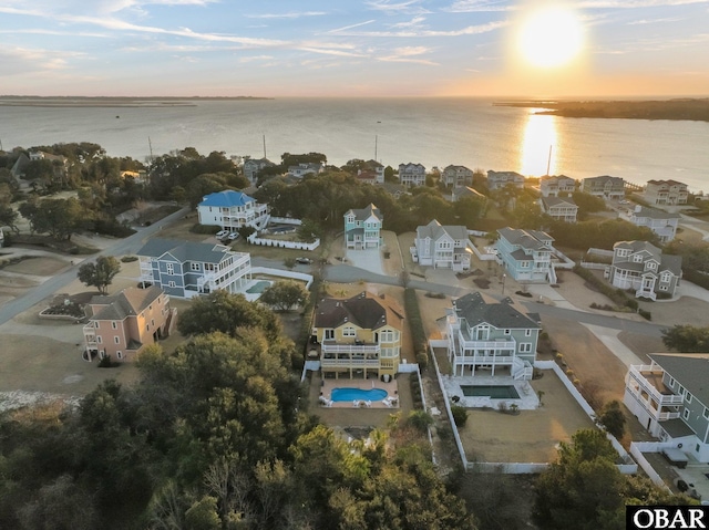 aerial view at dusk with a water view and a residential view