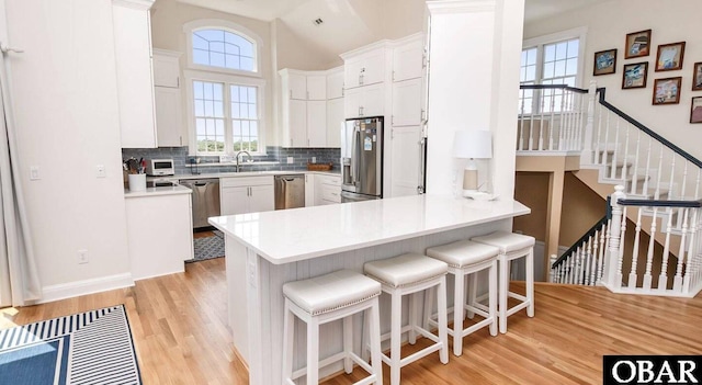 273 Whites Pt Lot 183, Corolla, NC 27927 - kitchen featuring appliances with stainless steel finishes, light wood-type flooring, backsplash, a peninsula, and high vaulted ceiling