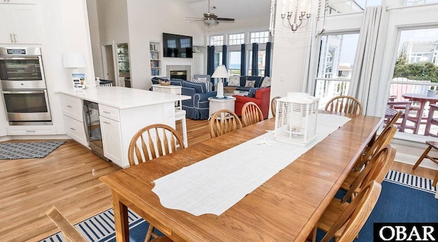 273 Whites Pt Lot 183, Corolla, NC 27927 - dining room featuring light wood-type flooring, a glass covered fireplace, a ceiling fan, plenty of natural light, and a towering ceiling