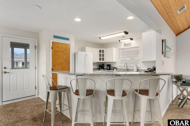 1045 Whalehead Dr Lot 27, Corolla, NC 27927 - kitchen featuring freestanding refrigerator, carpet flooring, light stone counters, white cabinets, and recessed lighting