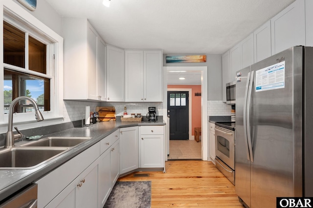 300 S Virginia Dare Trl Lot 1, Kill Devil Hills, NC 27948 - kitchen featuring appliances with stainless steel finishes, light wood-type flooring, white cabinetry, and tasteful backsplash