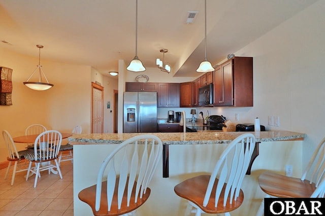 107 W Gray Eagle St Unit 112A, Nags Head, NC 27959 - kitchen featuring stainless steel fridge, black microwave, a peninsula, light tile patterned floors, and decorative light fixtures