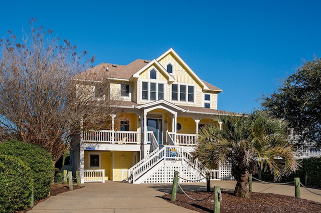 view of front of home featuring board and batten siding, covered porch, concrete driveway, and stairs