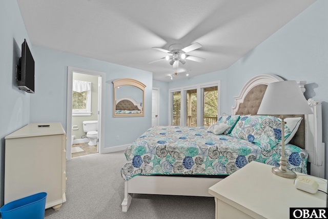 bedroom featuring baseboards, light colored carpet, ensuite bath, and a ceiling fan