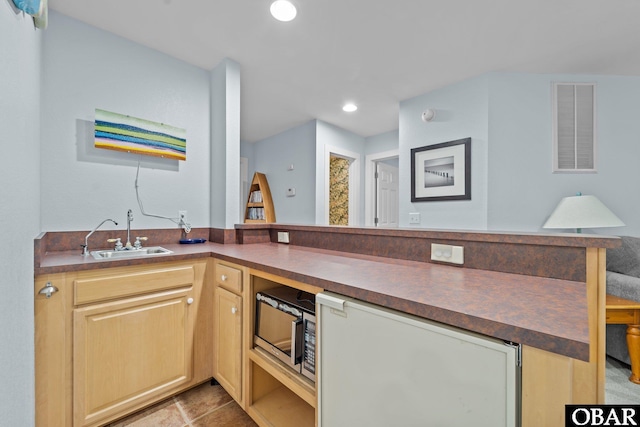 kitchen with dark countertops, visible vents, refrigerator, a sink, and stainless steel microwave