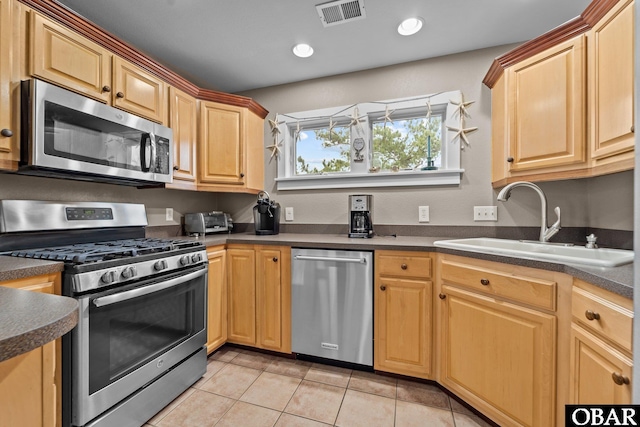 kitchen featuring visible vents, a sink, dark countertops, appliances with stainless steel finishes, and light tile patterned floors