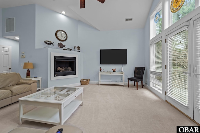 living room featuring visible vents, carpet floors, a high ceiling, a fireplace, and ceiling fan