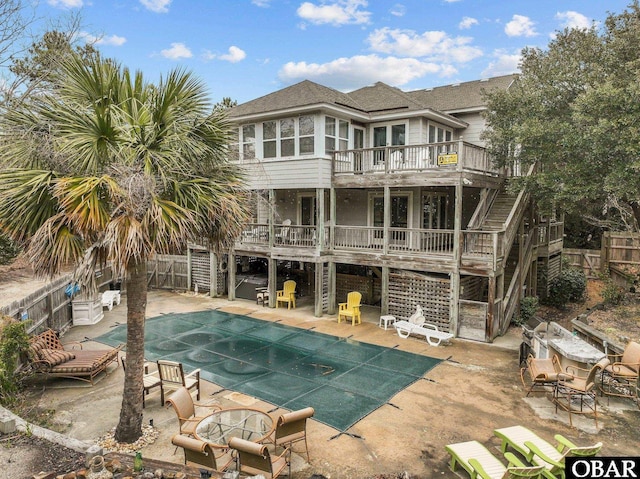 rear view of property featuring a deck, a patio, a fenced backyard, stairway, and a shingled roof