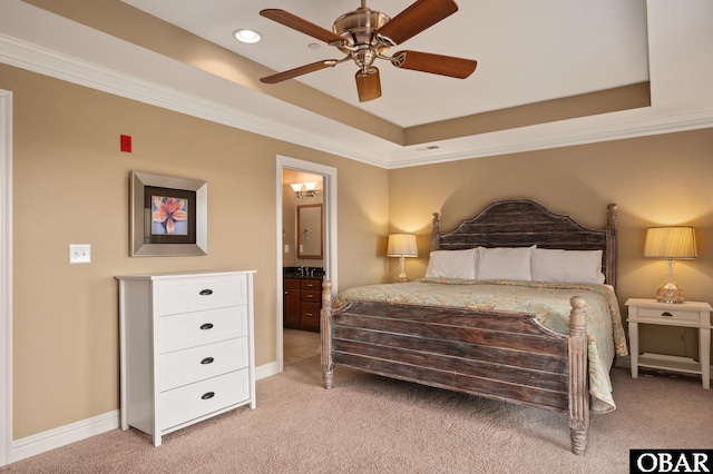bedroom featuring light carpet, a raised ceiling, ornamental molding, ensuite bath, and baseboards