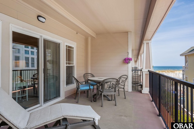 balcony with a water view and outdoor dining space
