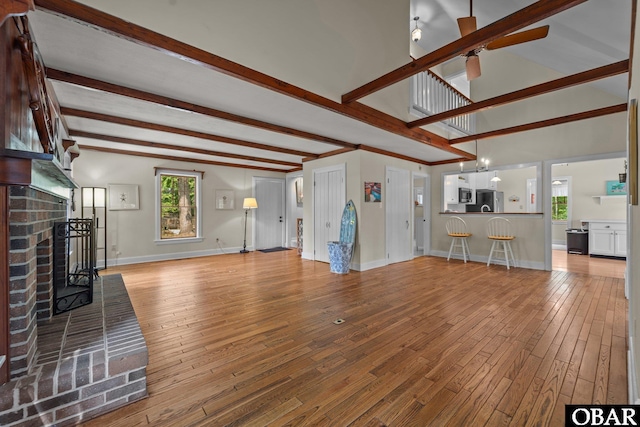 56 Ginguite Trl Lot 9, Southern Shores, NC 27949 - unfurnished living room featuring beamed ceiling, wood-type flooring, a brick fireplace, baseboards, and a ceiling fan