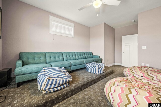 carpeted living room featuring ceiling fan and baseboards