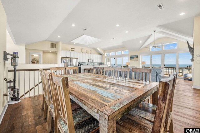 dining area with lofted ceiling with skylight, visible vents, ceiling fan, and light wood-style flooring