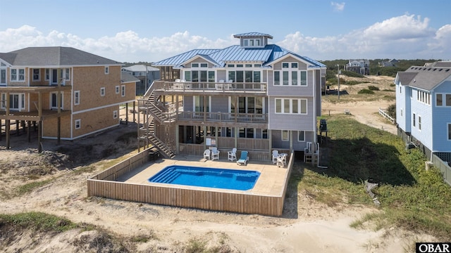 rear view of property featuring a fenced in pool, stairway, metal roof, a standing seam roof, and a patio area