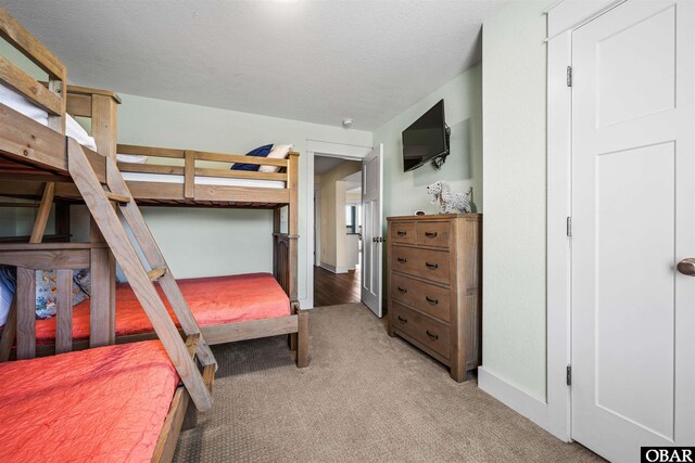 bedroom with baseboards, a textured ceiling, and light colored carpet