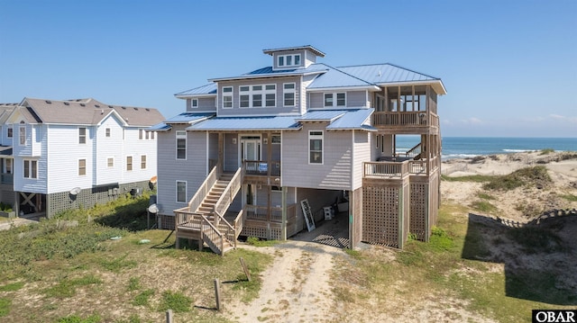 view of front of property with driveway, metal roof, a water view, a standing seam roof, and a carport