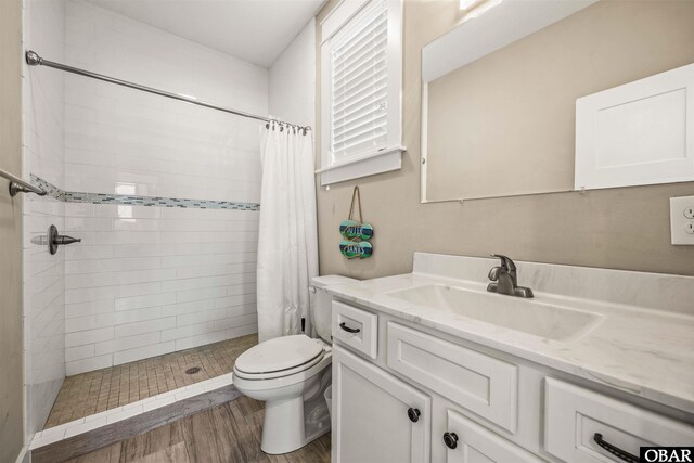 bathroom featuring toilet, wood finished floors, a shower stall, and vanity