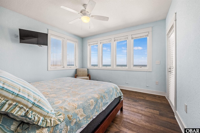 bedroom with dark wood finished floors, a ceiling fan, and baseboards