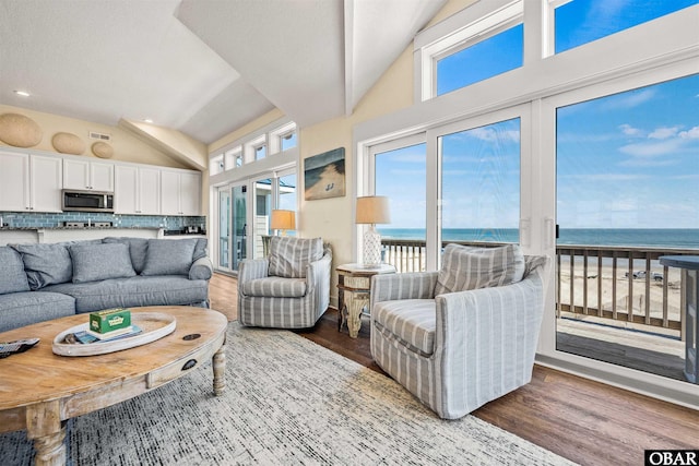 living room with a water view, vaulted ceiling, and wood finished floors