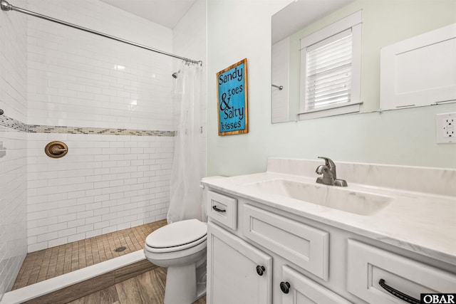 bathroom with a stall shower, vanity, toilet, and wood finished floors