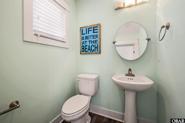 half bath featuring toilet, baseboards, and wood finished floors