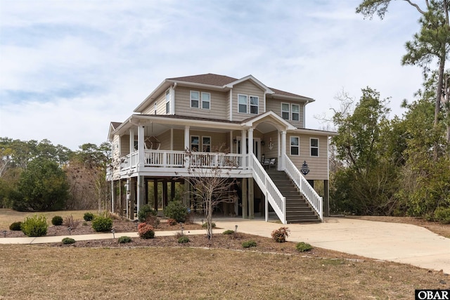 coastal home with a porch, stairway, concrete driveway, and a carport