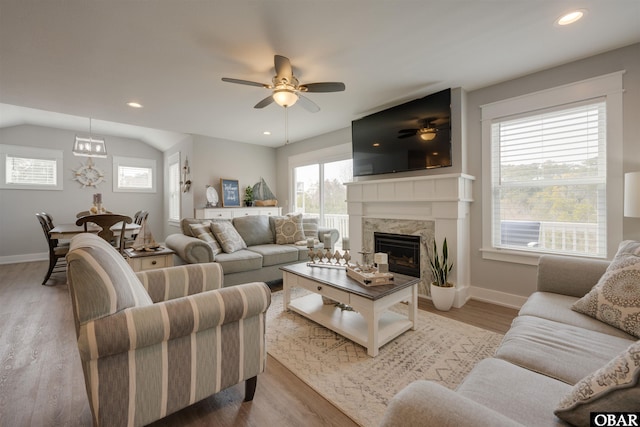 living area featuring a ceiling fan, recessed lighting, light wood finished floors, a premium fireplace, and lofted ceiling